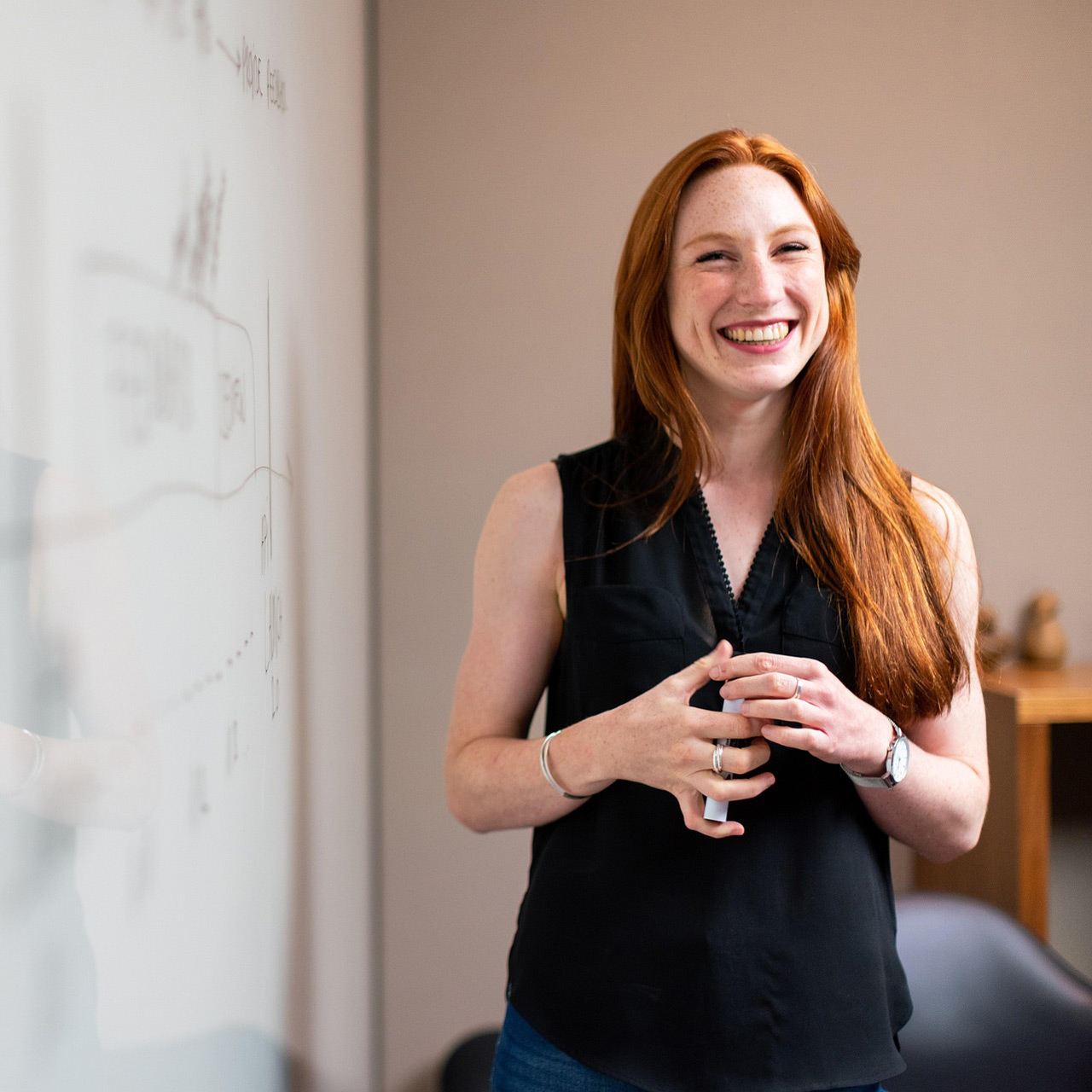 a smiling woman stands next to white board with strategy notes written on it