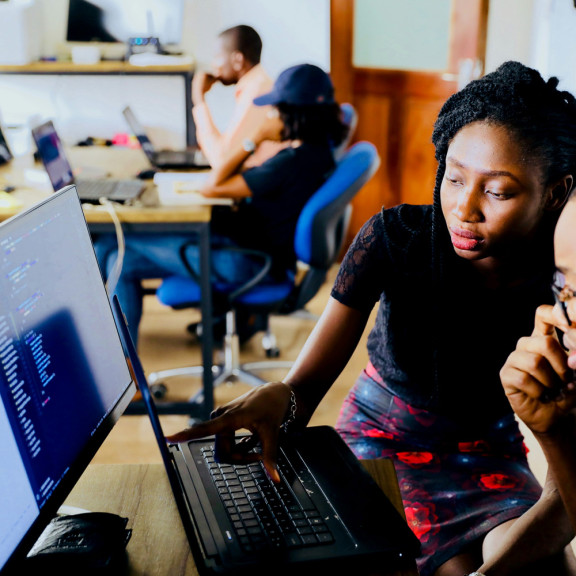 woman instructor discussing a strategy with man who faces a computer screen