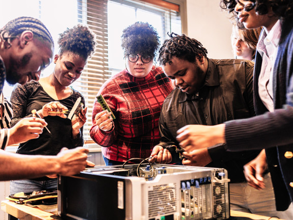 A group of people working together to fix a computer 