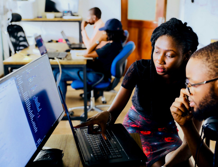 woman instructor discussing a strategy with man who faces a computer screen